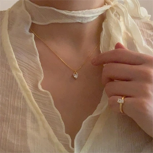 Elegant gold heart pendant necklace and rectangular gemstone ring set on female model
