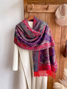 Detail of red and purple paisley scarf with fringes on a hanger over a beige coat