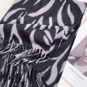 Detail shot of black and grey zebra pattern scarf with soft tassels on white background