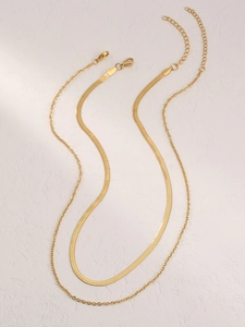 Close-up of golden layered snake chain and bead necklace with lobster clasp and extender