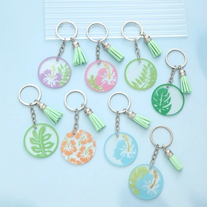 Acrylic tropical leaf flower keychains with matching tassels on a light blue background