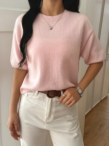 Detailed texture of a pink short sleeve knit sweater paired with white denim jeans