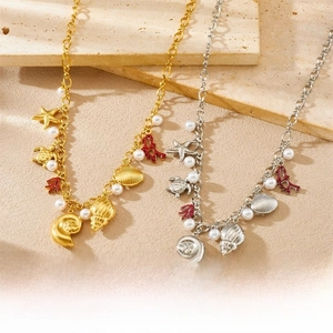 Close-up of gold and silver ocean charms with starfish, shells, and pearls on a sandy surface