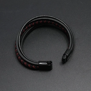 Close-up of braided leather bracelet featuring a black magnetic clasp on dark background