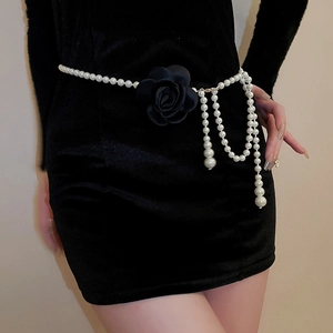Detail der eleganten Perlen-Taillekette mit schwarzer Stoffblume auf Samtkleid