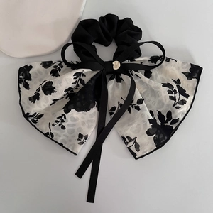 Detail of elegant black floral chiffon hair scrunchie with long ribbons and gold buckle