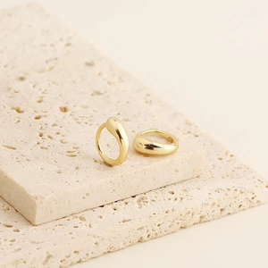 Detailed view of elegant gold S925 silver huggie hoop earrings on travertine stone
