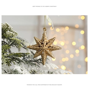 Detailed view of a golden star ornament on a snowy Christmas tree branch with warm bokeh lights