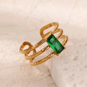Anello d'oro vintage con gemma verde smeraldo su sfondo di pietra bianca