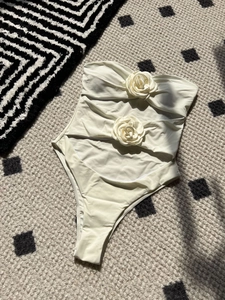 Detail of white cutout monokini featuring 3D rose appliques and strapless design