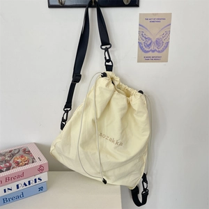 Detail view of beige drawstring backpack with sozakka embroidery and black nylon straps