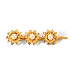 Détail d'une pince à cheveux marguerite dorée avec perles blanches sur fond blanc pur
