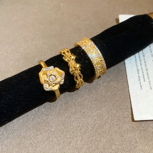 Close-up of three 24K gold plated flower and geometric rings on a velvet display