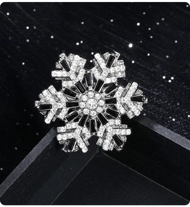 Macro shot of silver snowflake brooch with black and white crystals on a velvet jewelry box