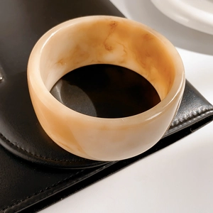 Macro detail of thick resin bangle with vintage amber pattern on black leather surface