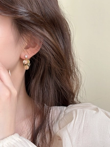 Gros plan de boucles d'oreilles grappe en résine plaqué or sur un mannequin femme