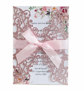 Detail of rose gold glitter laser cut invitation with pink satin ribbon and floral card