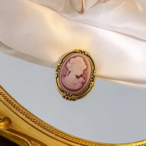 Macro shot of vintage golden cameo brooch with white lady profile on purple background