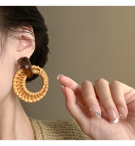 Close-up of vintage geometric rattan drop earrings with amber resin links and woven texture