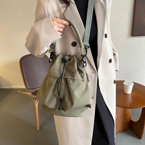 Vue détaillée du sac seau en nylon vert olive avec bandoulière grise réglable et cordon