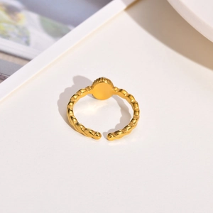 Detail of gold twisted band ring featuring a flat round surface on a minimal background
