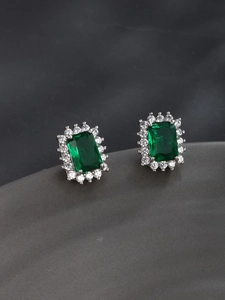 Macro view of emerald-cut green cubic zirconia earrings with white zircon halo set in silver
