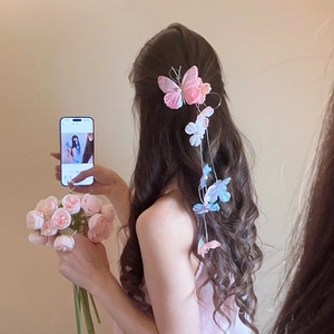 Detail of fabric butterfly hair clip with long tassel and pearls on wavy hair