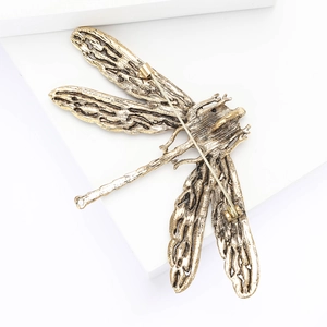Close-up of vintage gold dragonfly brooch with rhinestone details on white background