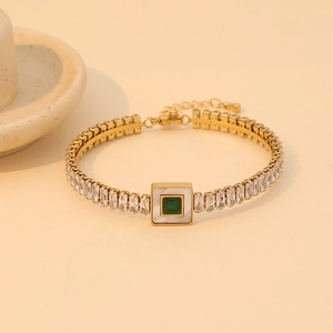 Gold stainless steel bracelet with zircon inlay and central green stone in top-down view