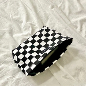 Detail view of large checkered makeup bag with Moonshine logo on white fabric