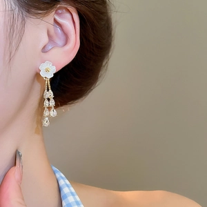 Detailed view of flower and teardrop crystal tassel earrings on a model’s ear
