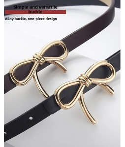 Close-up of golden bow-shaped alloy buckles on minimalist black and brown PU leather belts