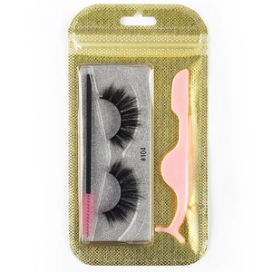 Detailed set featuring black false eyelashes with pink brush and applicator in gold pouch