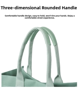 Detail of the light green canvas tote showing ergonomic leather-wrapped handles and stitching