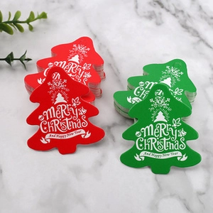 Dettaglio di etichette regalo a forma di albero di Natale rosse e verdi con scritte bianche