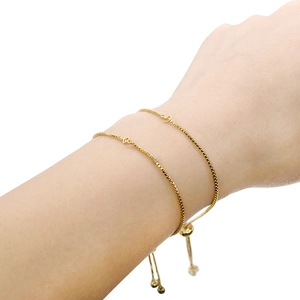 Detail of adjustable gold box chain bracelet with sliding clasp on a model's wrist