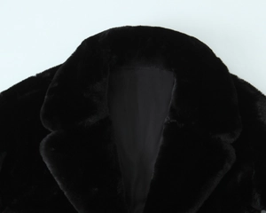 Détail macro du manteau en fausse fourrure noire avec col épais et texture pelucheuse