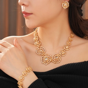 Detail of elegant gold-tone floral jewelry set featuring a necklace, bracelet and earrings