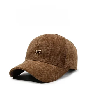 Detail of coffee brown baseball cap featuring herringbone texture and a gold metal bow