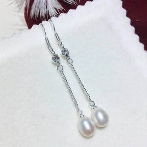 Dettaglio macro di orecchino con perla d'acqua dolce naturale e catena in argento lucido