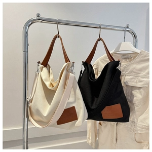 Detail of canvas tote bags in cream and black with stylish leather handles and shoulder straps