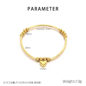Gros plan du bracelet en perles dorées en acier inoxydable avec pendentif cœur 3D