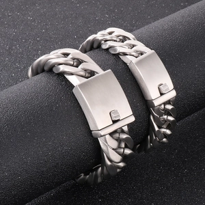 Macro shot of silver Cuban link bracelets with square clasp detail on black background