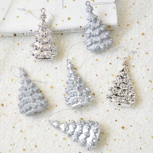 Close-up of glitter and mirror silver Christmas tree ornaments on white festive fabric