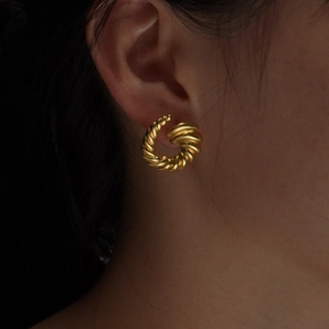 Elegant gold croissant-style C-shaped spiral earrings worn by a model in a close-up view
