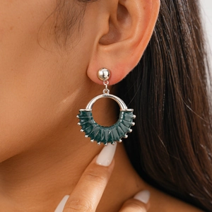 Close-up of model wearing geometric round earrings with dark green leather weaving