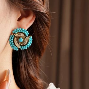 Close-up of vintage flower earrings with turquoise and rhinestones on a female model
