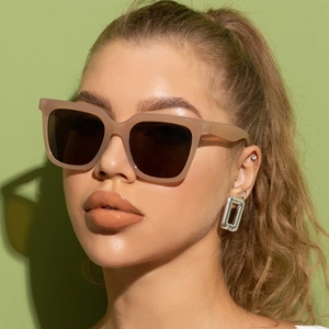 Close-up of translucent pink oversized square sunglasses with dark lenses on female model
