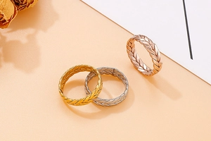 Dettaglio della trama a foglia intrecciata di anelli in finitura oro, argento e rosa