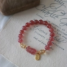 Detail of pink crystal beaded bracelet with lucky gold charm on vintage script background